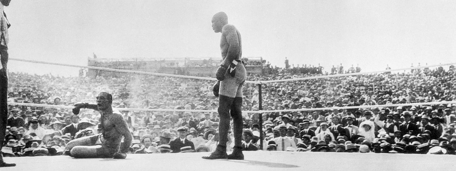 Jack Johnson standing over his opponent in the ring