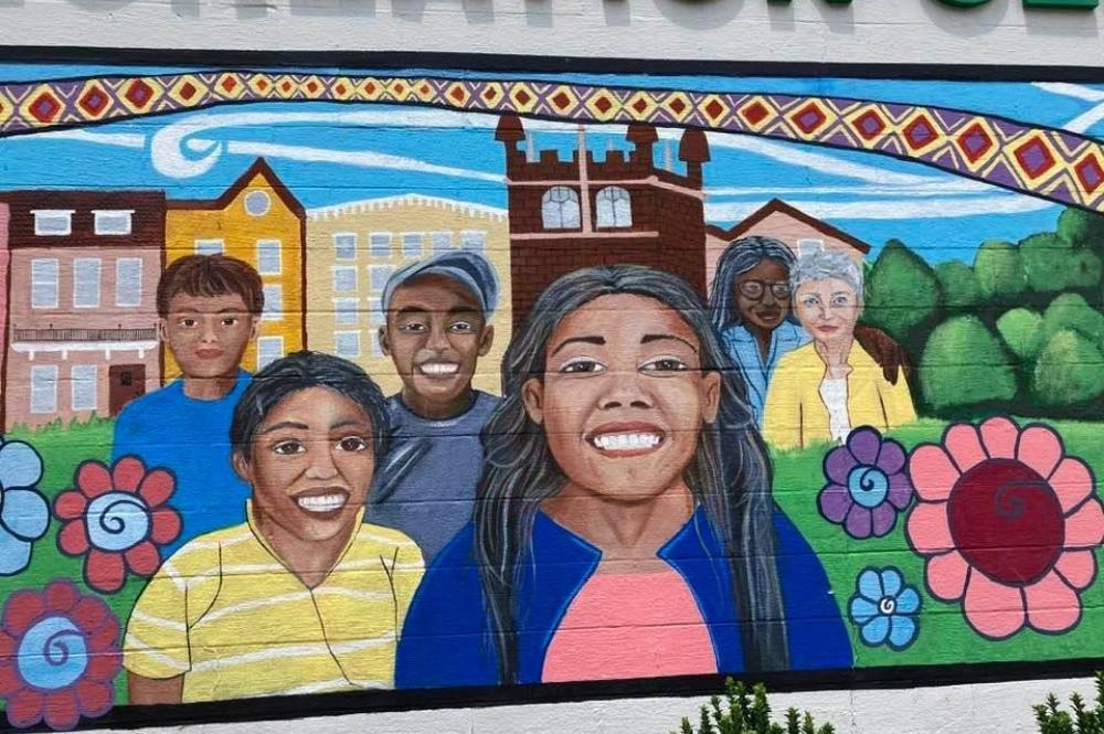 Mural of children's faces outside on brick wall