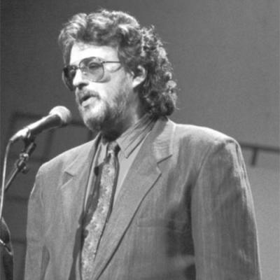 Gerry Goffin singing at the mic. This photo is in black and white. 