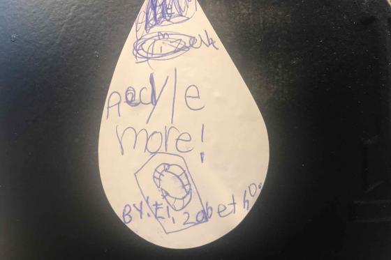 A photo of an oil droplet. It reads 'recycle more!' in a child's handwriting, and is signed from Elizabeth. 